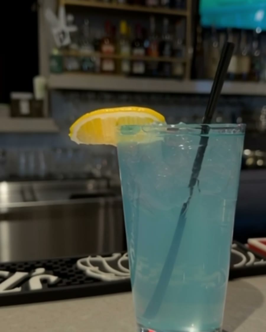 A blue cocktail with a lemon wheel on the bar at Birdie Lounge